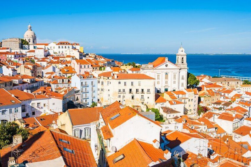 A coastal town with red-tiled rooftops, white buildings, and a prominent church with a dome. 5