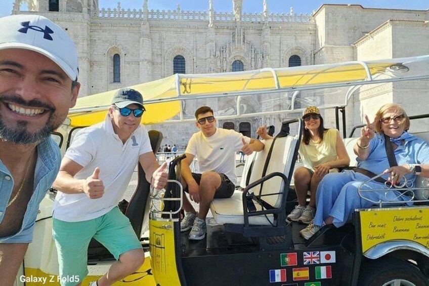 A group of people on a sightseeing bus with a historic building in the background. 1