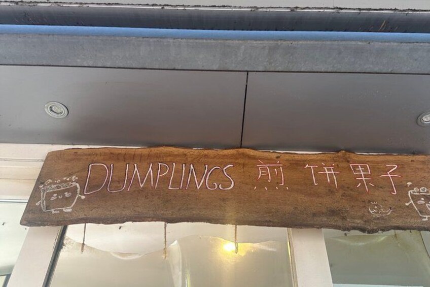 A wooden sign with the text 'DUMPLINGS' and a drawing of a dumpling. 2