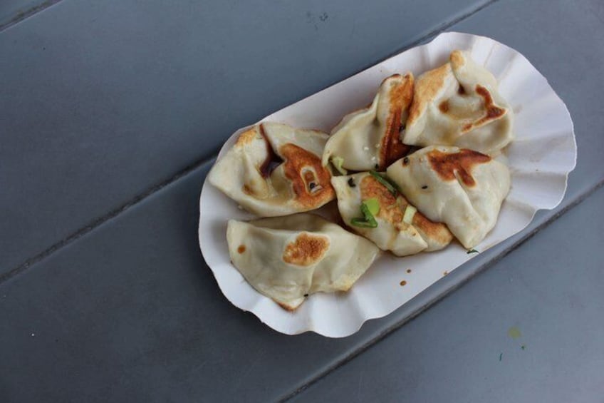 A plate of dumplings with a scalloped edge on a gray surface. 3