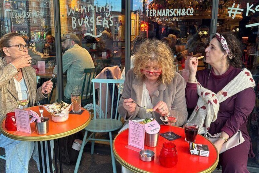 Three people dining at a restaurant with a red table, menu, and a glass of red beverage. 1