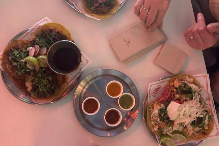 A table with various dishes, including tacos and a plate with a drink and condiments. 4