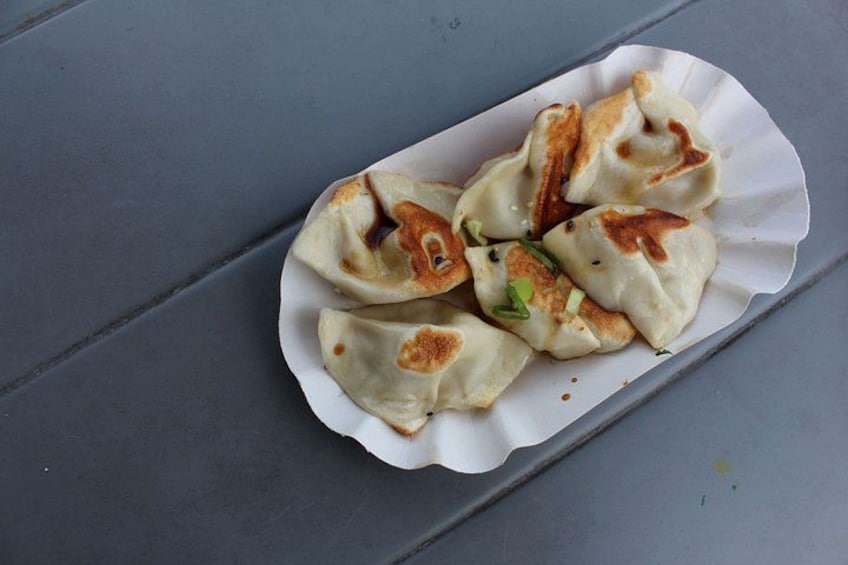 A plate of dumplings with a scalloped edge, placed on a grey surface. 3