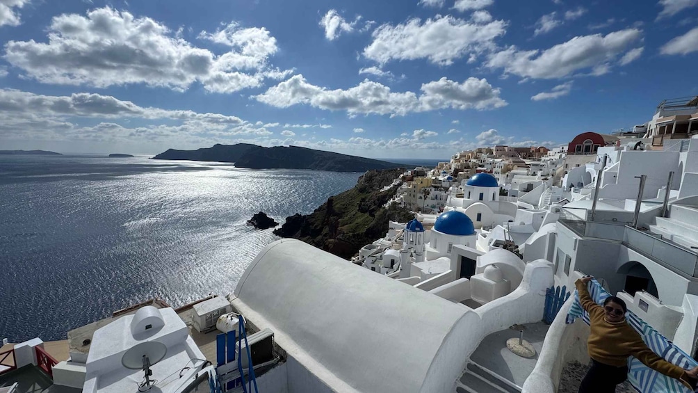 A coastal town with white buildings and blue domes, overlooking the sea. 1