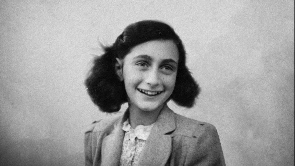 A person with a blurred face, wearing a collared shirt and a jacket. 1