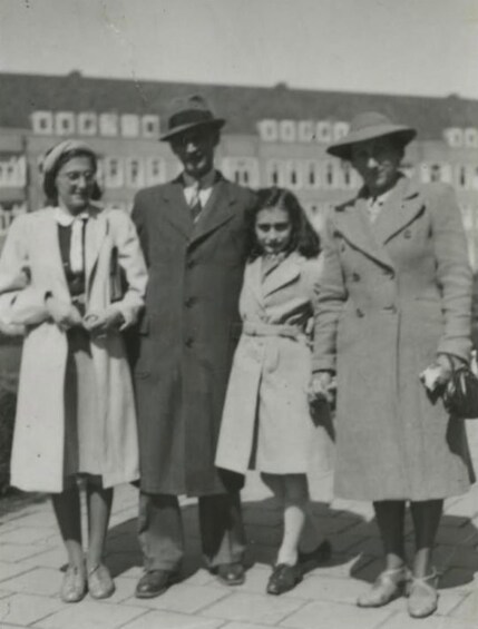 Four people standing in front of a building with large windows and a sign. 4