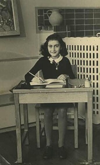 A person sitting at a table with a book, a lamp, and a vase in the background. 5