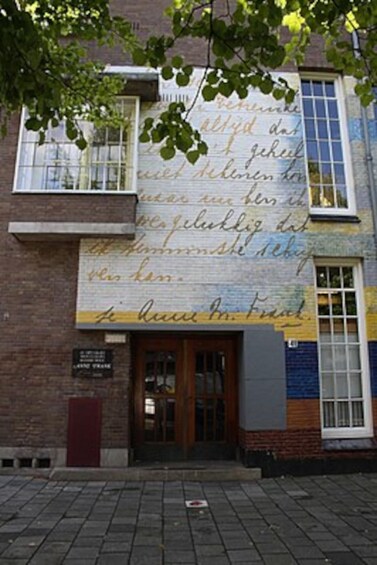 A building with a large mural on the side, a wooden door, and a brick facade. 2