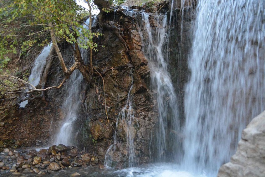 A waterfall cascading over rocky terrain with trees around. 1