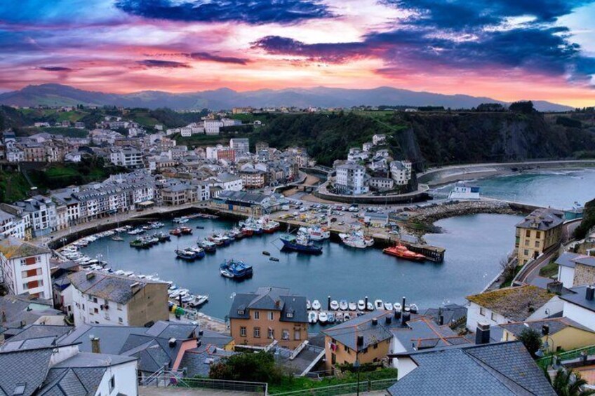 A coastal town with a marina, buildings, and a sunset. 5