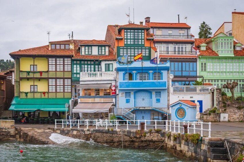 Colorful buildings along a waterfront with a stone wall and a white fence. 3