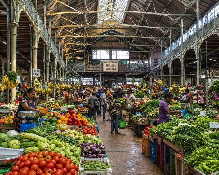 A bustling indoor market with various fresh produce stalls and a high ceiling with metal beams. 3
