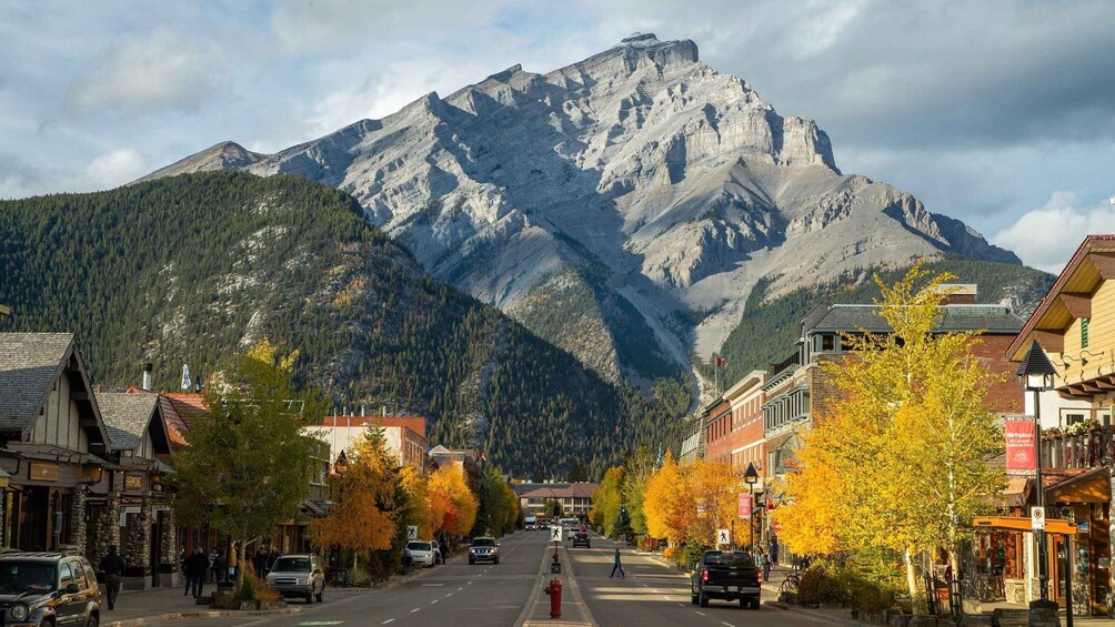 A mountain town street with autumn foliage, buildings, and a prominent mountain in the background. 3