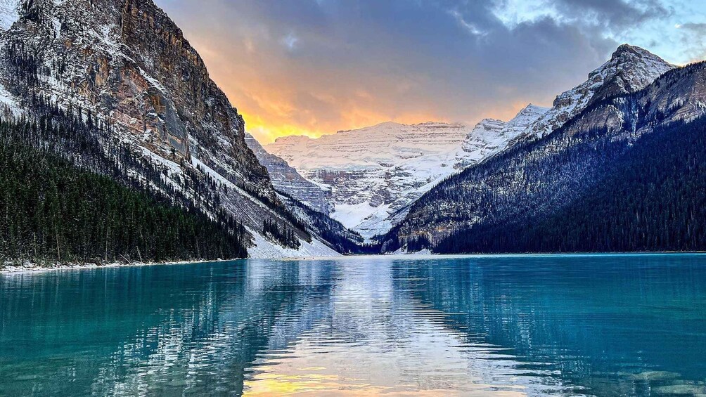 A snow-covered mountain range with a clear lake reflecting the sky. 1