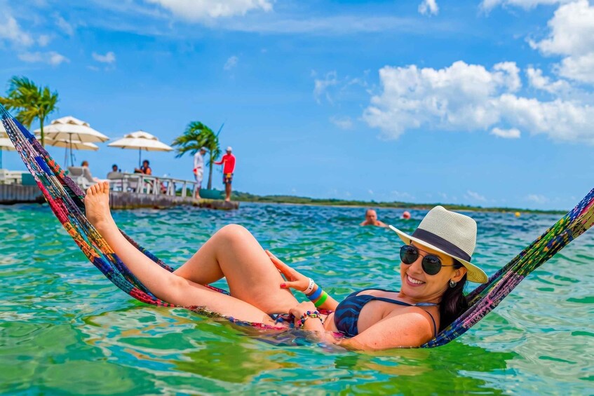 A person relaxing in a hammock in a clear blue pool with palm trees and umbrellas in the background. 3