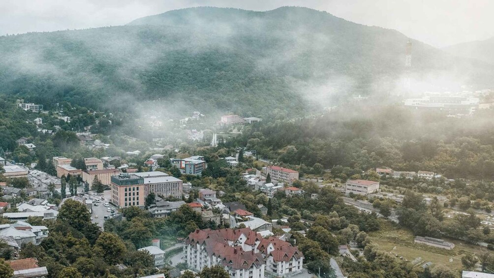A town nestled in a valley with a mountain backdrop, surrounded by greenery and featuring a mix of residential and commercial buildings. 4