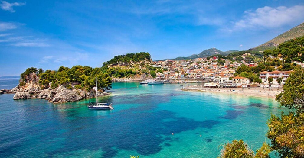 A coastal town with clear turquoise waters, a sailboat, and lush greenery. 3