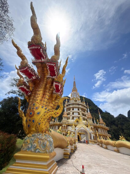 Une statue de dragon doré, un temple doté de nombreuses flèches et un paysage montagneux en arrière-plan. 1