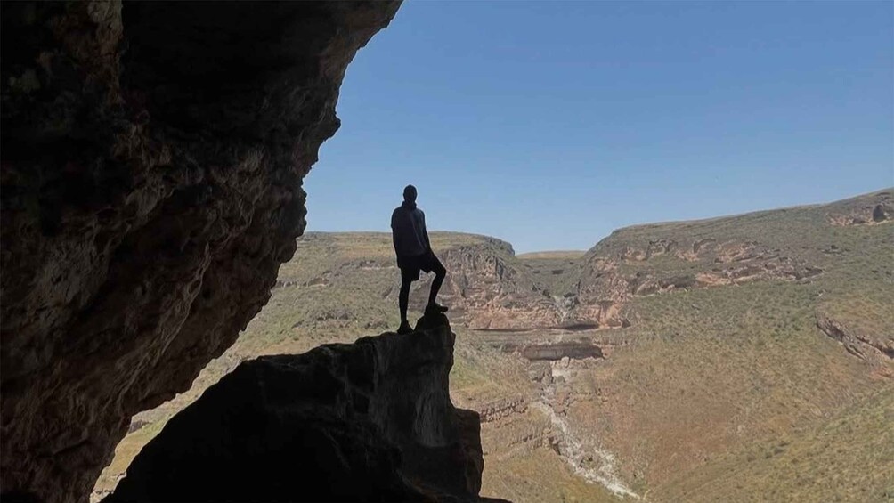 Una persona in piedi su una formazione rocciosa, con un canyon sullo sfondo. 4