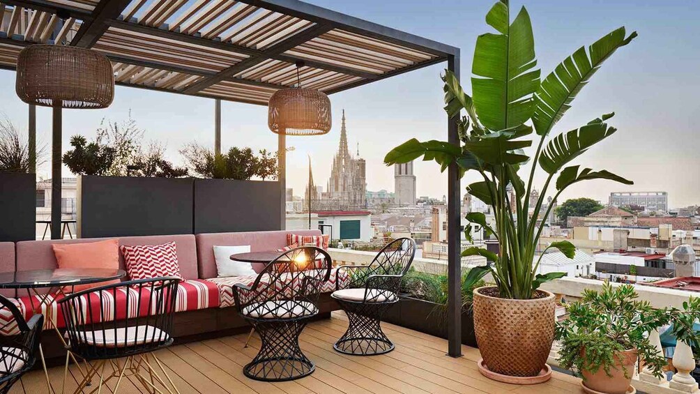 A rooftop terrace with a sofa, chairs, and potted plants. 3
