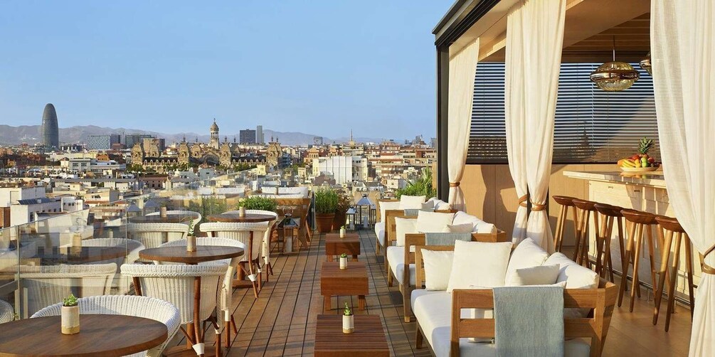 A rooftop terrace with wicker furniture and a cityscape view. 5