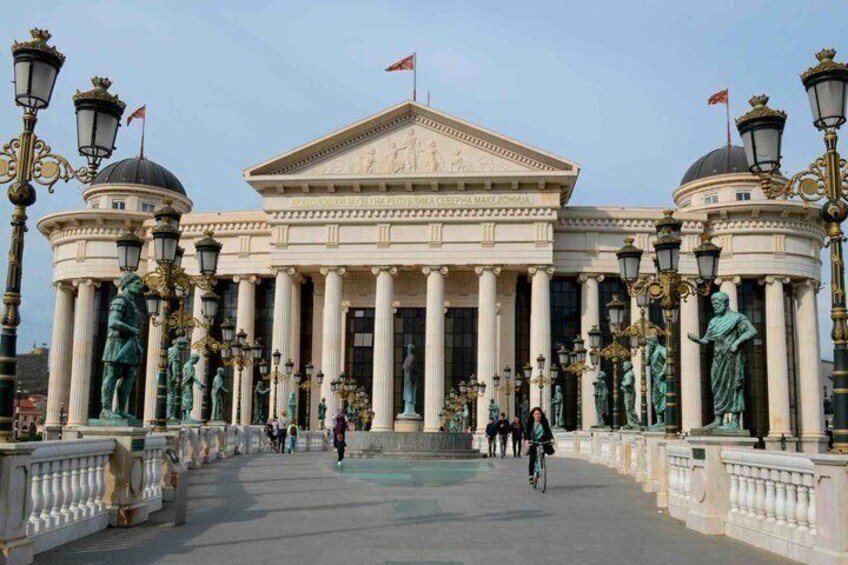A neoclassical building with columns, statues, and a flag. 3