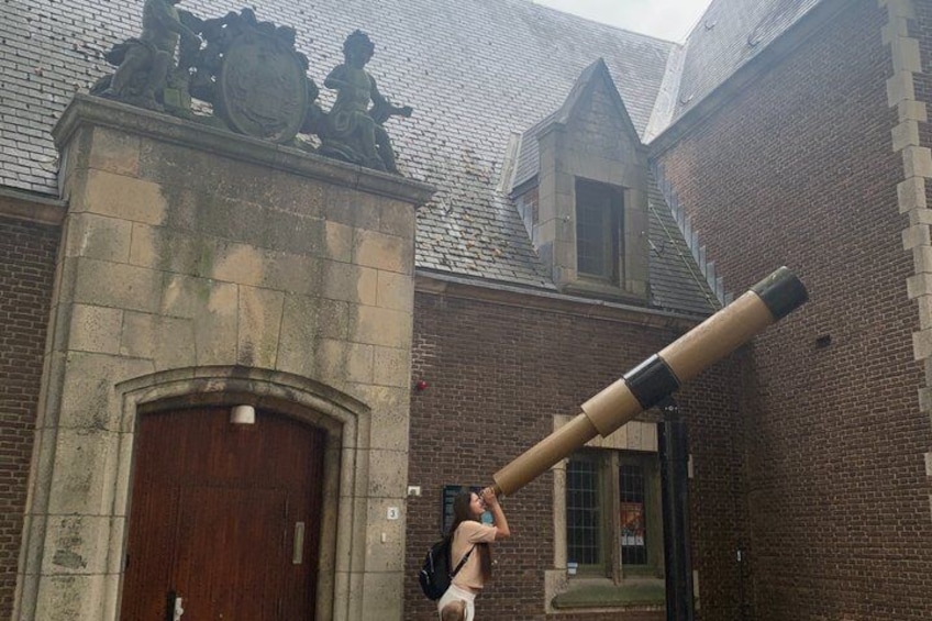 A large cannon in front of a historic building with a brick facade and a wooden door. 1