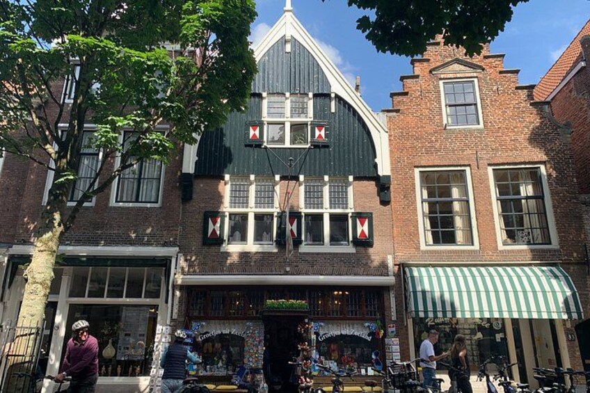 A historic building with a black roof and white trim, a green awning, and a bicycle parked outside. 5