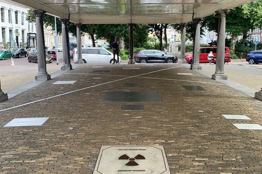A covered pedestrian walkway with columns, a brick ground, and a metal plate with text. 2
