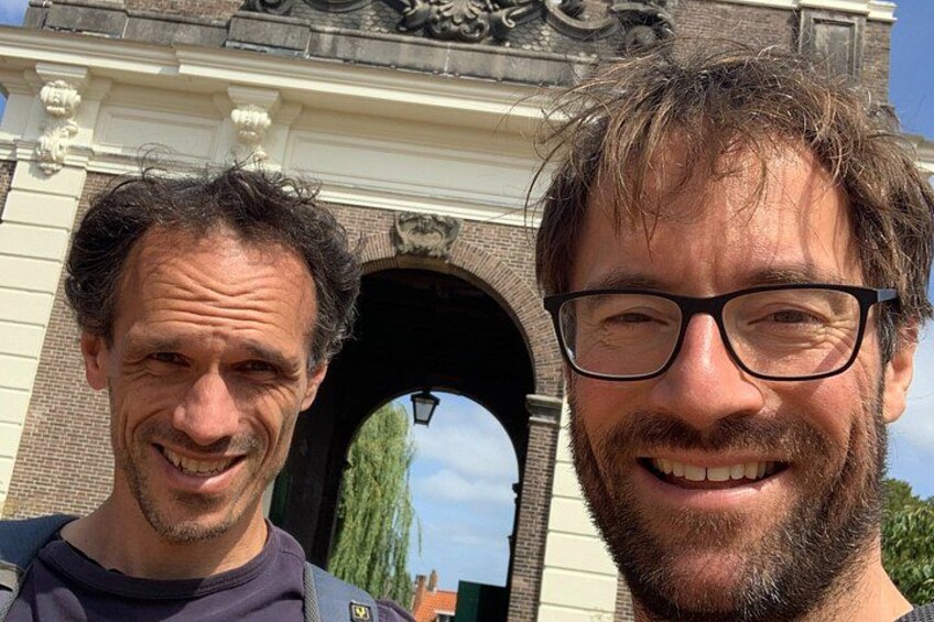 Two individuals in front of a historical archway with intricate carvings. 3