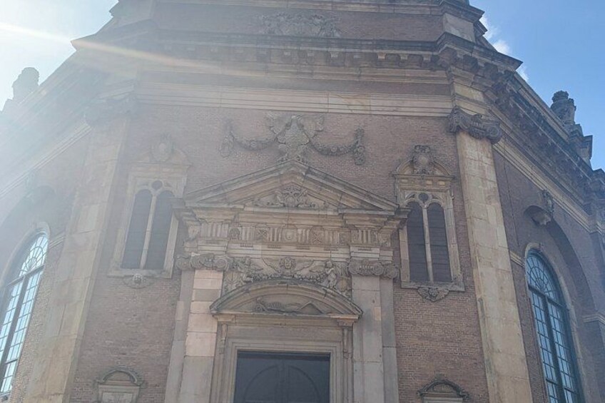 A historic building with a large arched entrance, decorative stonework, and tall windows. 4