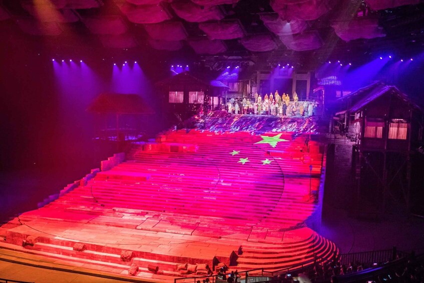 A theater stage with a circular arrangement of steps and a group of performers at the front. 5