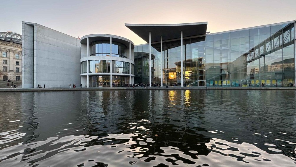 A modern building with a reflective glass facade and a water feature in front. 1