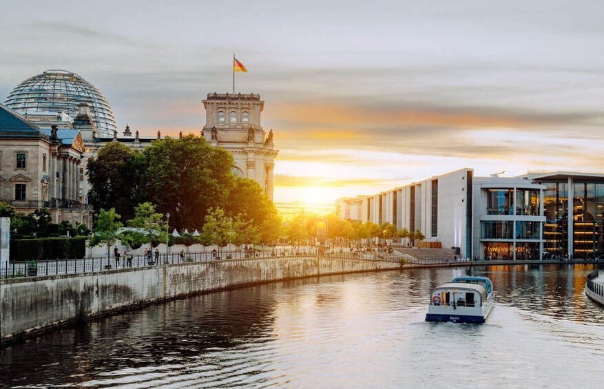 A river with a boat, a modern building, and a classical monument during sunset. 4