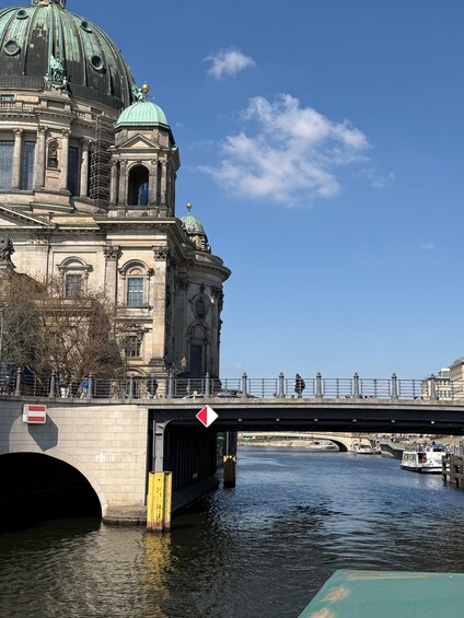 A historic building with a green dome and a bridge over a river. 3