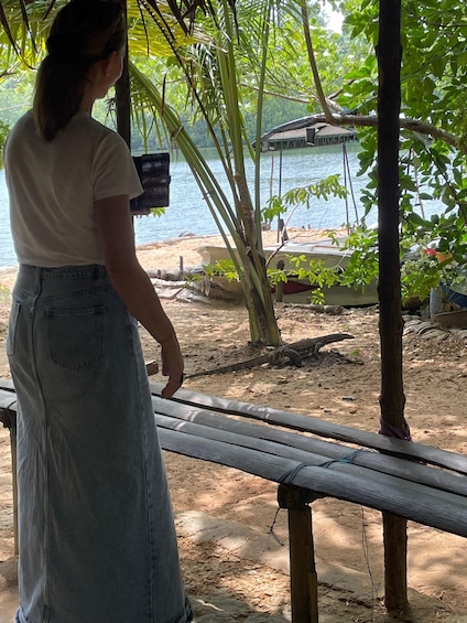 A person standing on a wooden bench overlooking a beach with boats and a hut in the background. 5