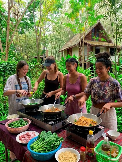 Four people cooking outdoors with a variety of ingredients and cooking utensils. 2