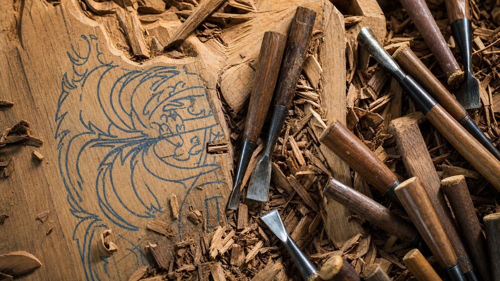 A wooden carving with a carved face surrounded by wood shavings and carving tools. 4