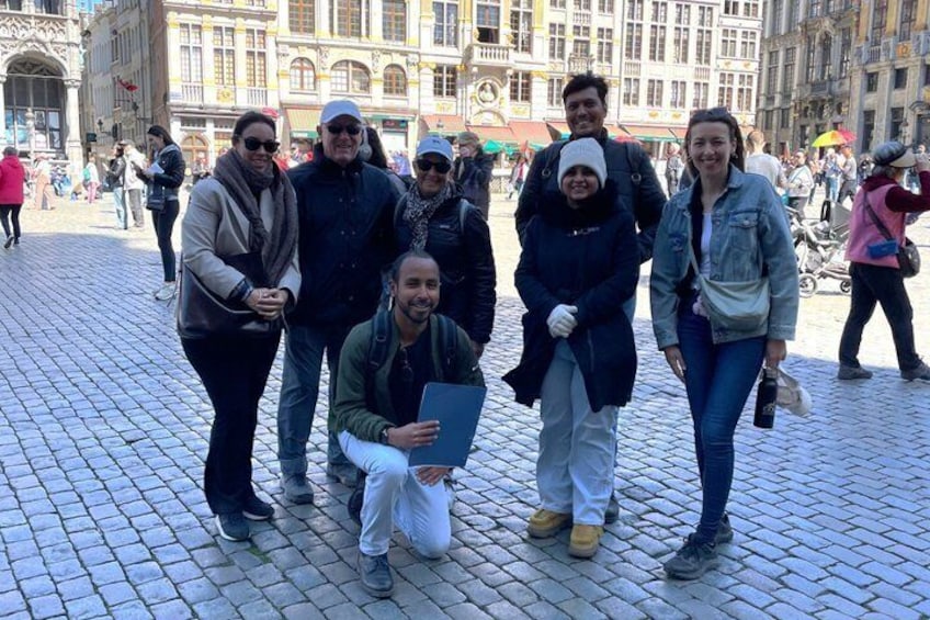 A group of people posing in a cobblestone square with historic buildings in the background. 3
