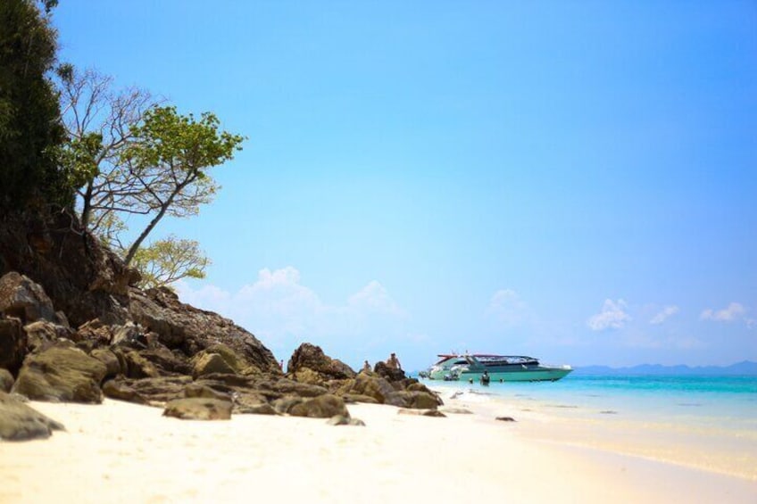A beach with white sand, clear turquoise water, and a cruise ship in the distance. 2