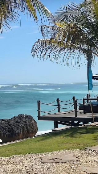 A beach with a wooden deck, palm trees, and the ocean. 1