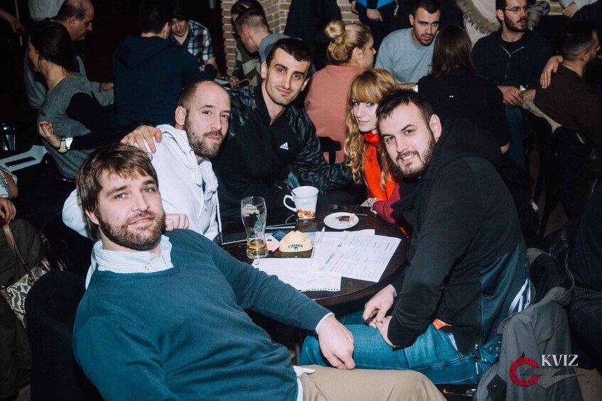 A group of people seated around a table with papers and a cup. 5