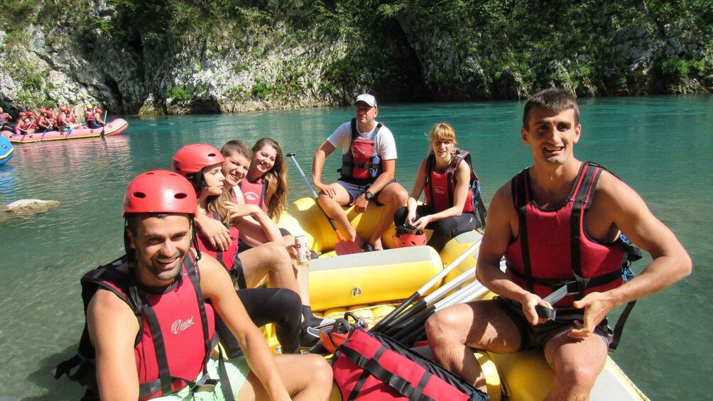 A group of people in a yellow raft on a calm river surrounded by rocky cliffs. 3