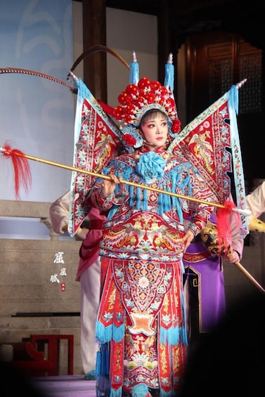 A person in traditional costume with elaborate headgear and a staff. 1