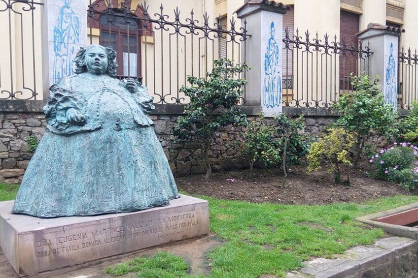 A statue of a woman in a dress, a stone wall, and a fence with decorative elements. 4