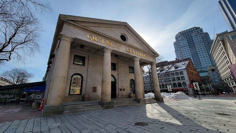 A classical building with columns and a sign reading 'QUINCY MARKEIT.' 1