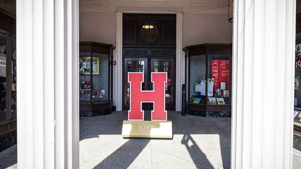 A building entrance with a large red 'H' sign and a plaque reading 'The Coop Harvard.' 2