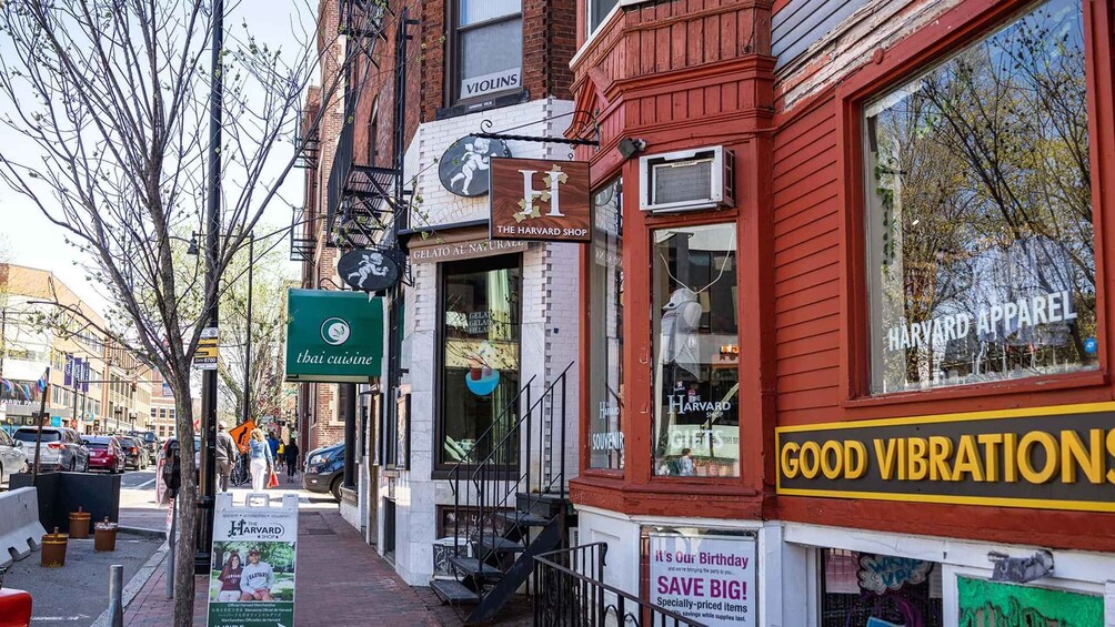 A street with various shops including a Harvard shop, a Thai cuisine restaurant, and a Harvard apparel store. 5