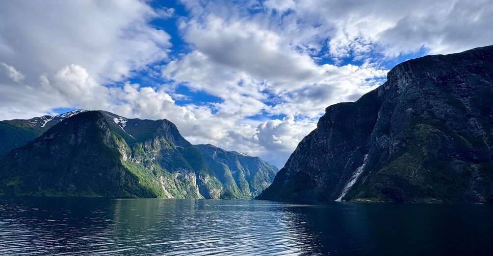 A fjord with steep mountains, a clear sky, and a calm body of water. 4