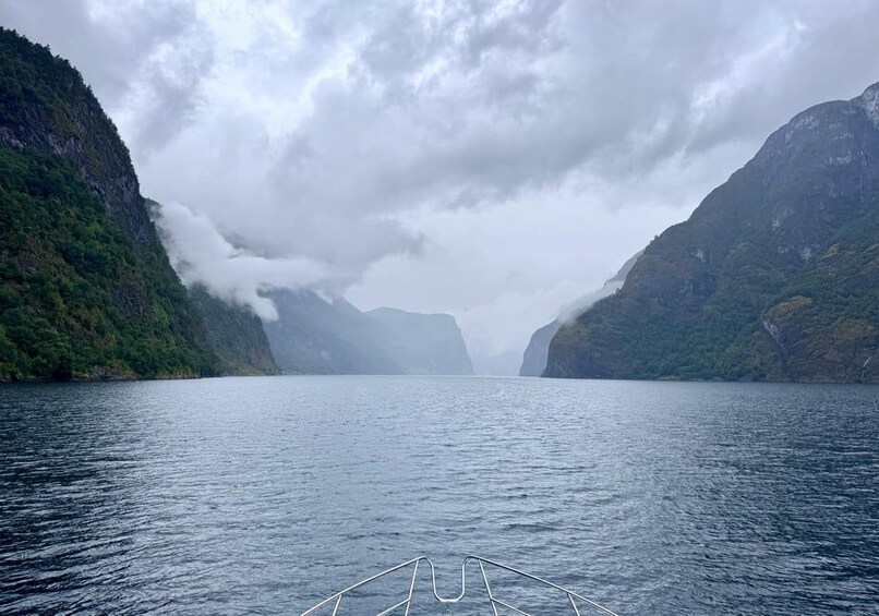 A calm lake surrounded by steep, forested cliffs under a cloudy sky. 3